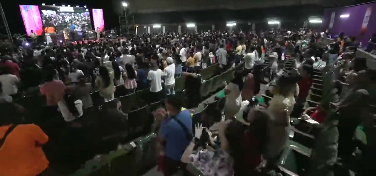 A wide view of the congregation filling the tiered seating of the arena